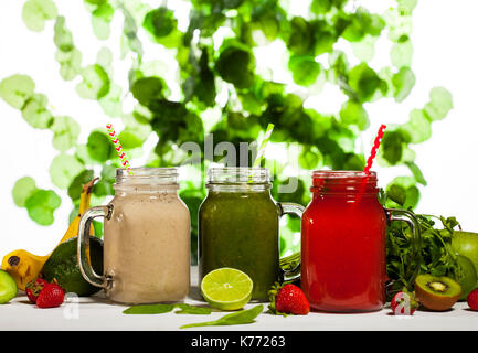 Assortiment de smoothies de fruits et légumes dans des bocaux en verre avec paille sur fond vert. Banque D'Images