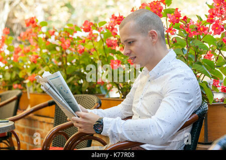 Jeune homme d'affaires est assis dans un café et lisant le journal Banque D'Images