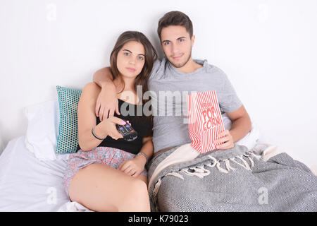 Jeune couple à regarder des films au lit et eating popcorn. à l'intérieur. Banque D'Images