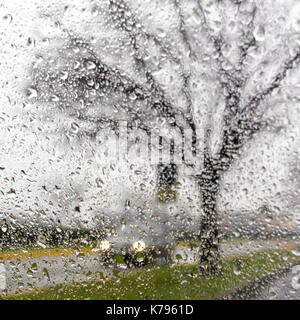 Silhouette voiture floue vu par gouttes d'eau sur le pare-brise de voiture Banque D'Images