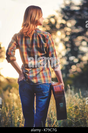 Fille avec une guitare dans les mains sur l'air libre de l'automne, les puits dans le côté. Banque D'Images