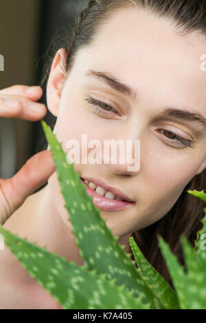 Jeune femme toucing aloe vera Banque D'Images