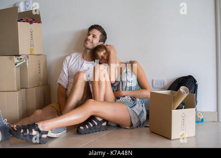 Young couple sitting in new house with cardboard boxes Banque D'Images