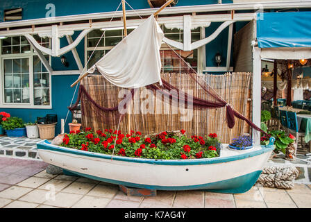 Bateau en bois bleu sur la côte, qui sert de décoration dans un café avec des fleurs, et d'autres détails Banque D'Images