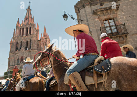 Des cow-boys à cheval se baladent dans le jardin Allende devant l'église arnaque de San Miguel Arc‡ngel très ornée pendant la première journée de célébrations marquant la Journée de l'indépendance mexicaine connue sous le nom de Cry of Dolores le 15 septembre 2017 à San Miguel de Allende, Mexique. Banque D'Images