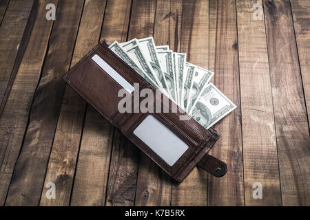 L'argent dans une pochette en cuir sur fond de bois. one hundred dollar bills. Banque D'Images