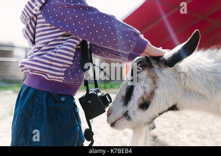 Portrait girl petting goat Banque D'Images