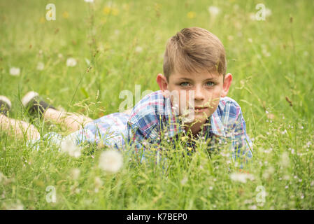 Garçon couché sur le ventre dans l'herbe, portrait Banque D'Images