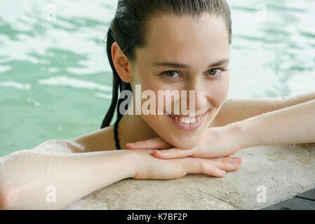 Woman in swimming pool at edge resting head on arms Banque D'Images