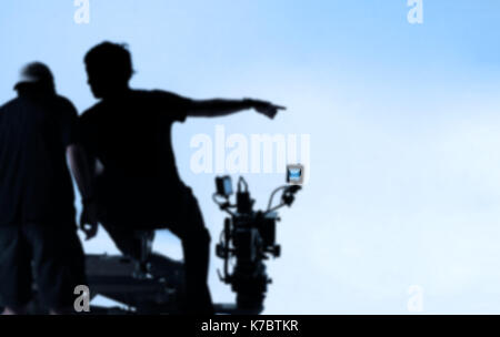 Image floue dans les coulisses de la production de l'appareil photo et de parler de l'homme et de l'équipement de tir situé dans le grand atelier. Banque D'Images