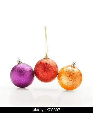 Trois boules de Noël colorées brillantes contre fond blanc. Banque D'Images
