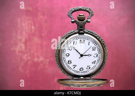 Ancienne montre de poche sur mur rouge grunge background Banque D'Images