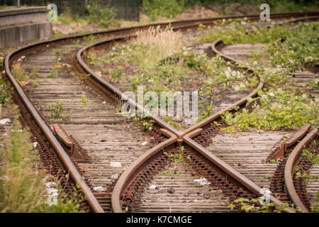 Voie ferrée à côté d'une ancienne gare plate-forme avec un côté voies rouillées Banque D'Images