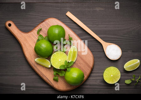 Limes frais sur une planche à découper sur la table en bois avec une cuillère de sel. Vue de dessus, l'arrière-plan. Banque D'Images