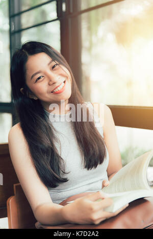 Profitez de moments de détente avec lecture du livre, les femmes asiatiques thai teen sourire avec réserve en coffee shop vintage color tone Banque D'Images