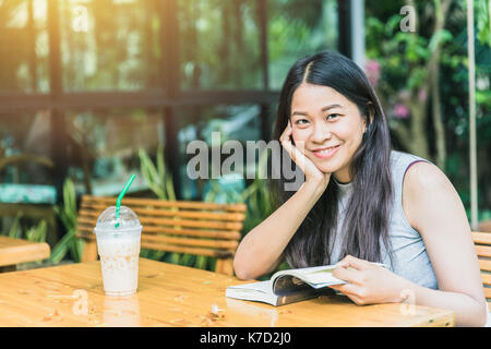 Profitez de moments de détente avec lecture du livre, les femmes asiatiques thai teen sourire avec réserve en coffee shop vintage color tone Banque D'Images