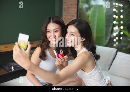 Deux jeunes filles asiatiques et les ongles des orteils de peinture sur un lit dans la salle de séjour Banque D'Images