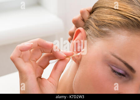 Close-up of young woman cleaning coton-tige avec de l'oreille Banque D'Images