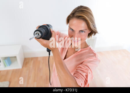 Portrait of happy young woman holding drill machine Banque D'Images