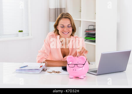 Femme heureuse avec des projets de mise en pièce de tirelire à 24 Banque D'Images
