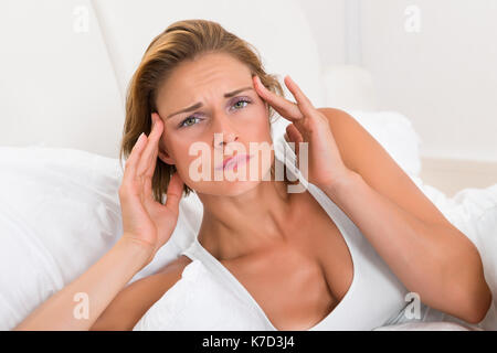 Portrait de jeune femme ayant des maux de tête au lit Banque D'Images