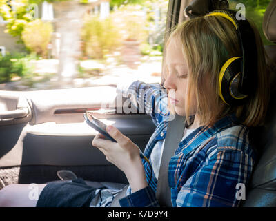 Boy looking at mobile phone pendant que vous écoutez votre musique en voiture Banque D'Images