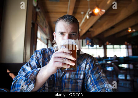 Portrait d'un homme ayant la bière tout en sitting in restaurant Banque D'Images