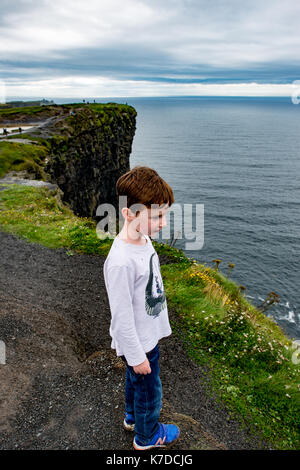 Garçon à la recherche jusqu'aux falaises de Moher attraction touristique en Irlande Banque D'Images