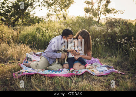 Happy Family sitting on picnic blanket avec chien au domaine Banque D'Images