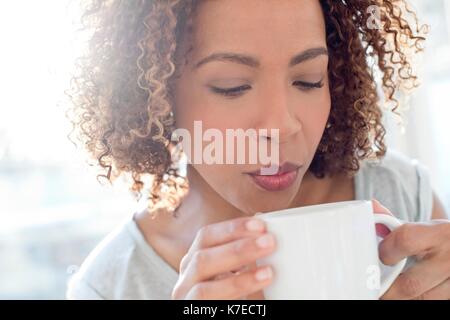 Mid adult woman blowing sur le café. Banque D'Images