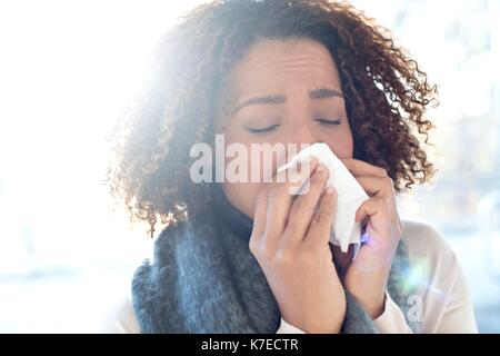 Mid adult woman blowing nose sur les tissus. Banque D'Images