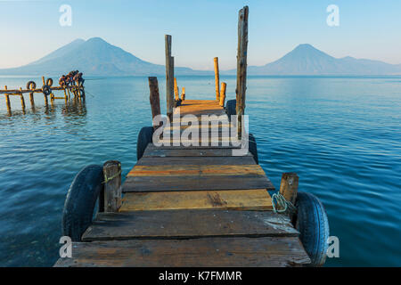 Les jeunes garçons sur un quai de pêche par le lac Atitlan au lever du soleil avec volcan San Pedro dans le fond près de Panajachel au Guatemala, en Amérique centrale. Banque D'Images