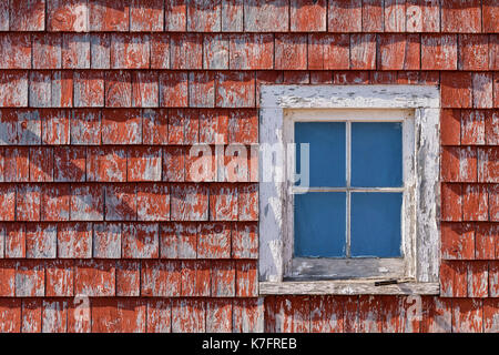 Une petite fenêtre dans un petit bâtiment avec parement rouge rustique secouer. Banque D'Images