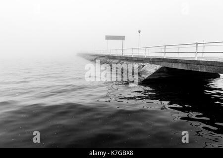 Un quai sur un lac au milieu du brouillard Banque D'Images