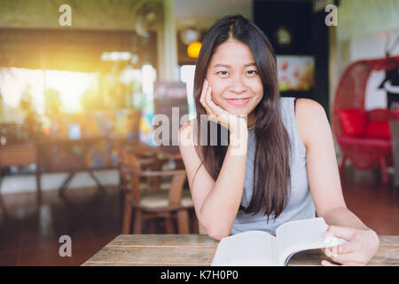 Profitez de moments de détente avec lecture du livre, les femmes asiatiques thai teen sourire avec réserve en coffee shop vintage color tone Banque D'Images