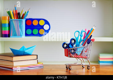 Retour à l'école panier de provisions sur la table en bois. panier rempli de avec des fournitures scolaires. Banque D'Images