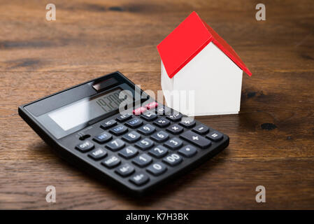 Close-up of miniature house avec la calculatrice sur table en bois Banque D'Images