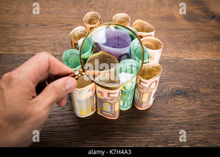 Close-up of a woman's hand holding loupe sur les billets en euros Banque D'Images