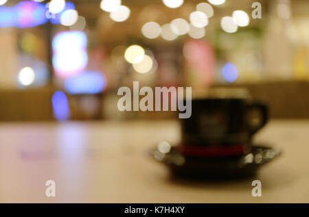 Image floue d'une tasse de boisson chaude sur table en bois dans le café avec des lumières bokeh Banque D'Images