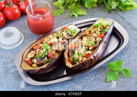 Aubergines farcies aux champignons, oignons, carottes, tomates et noix sur une plaque de métal sur un fond gris.. nourriture végétarienne saine alimentation concept. Banque D'Images