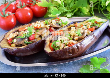 Aubergines farcies aux champignons, oignons, carottes, tomates et noix sur une plaque de métal sur un fond gris.. nourriture végétarienne saine alimentation concept. Banque D'Images