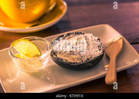 Couper la moitié de bagel fromage à la crème avec du charbon sur cuillère en bois en couleur vintage style, selective focus Banque D'Images