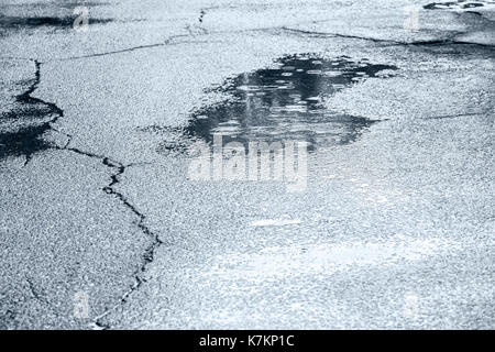 Les flaques d'eau avec de l'eau et de gouttes de cercles sur la route d'asphalte humide craquelé Banque D'Images