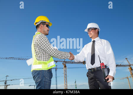 Avec l'ingénieur en construction worker shaking hands at construction site Banque D'Images