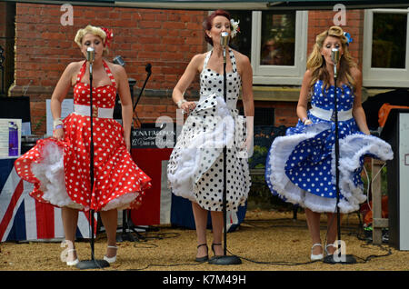 Trois femmes en robes polkadot, chantant des chansons des années 40 Banque D'Images