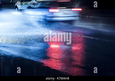 Le trafic urbain croisement route inondée en raison de pluies durant la nuit. de flou. Banque D'Images