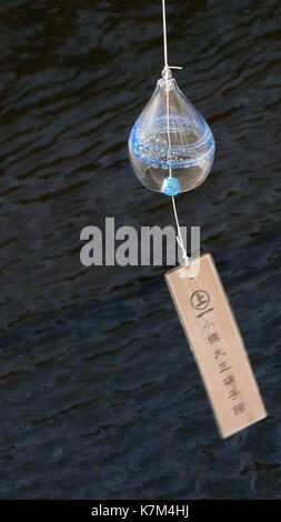 Photos de verticale et horizontale des japonais rond coloré main soufflée petits carillons de vent qui pendait sur le fil plus de Otaru canal dans quartier commerçant. Banque D'Images