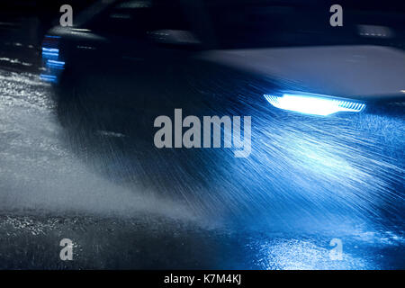 Voiture floue en mouvement. location de pulvériser de l'eau qu'elle entraîne lors de fortes pluies. Banque D'Images