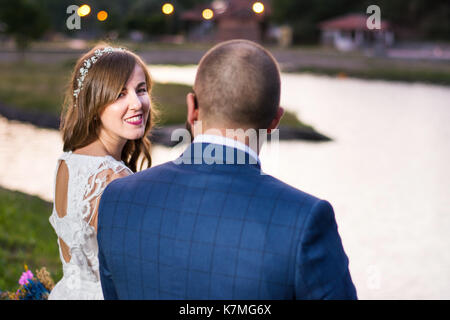 Bride and Groom assis au bord du lac à la soirée Banque D'Images