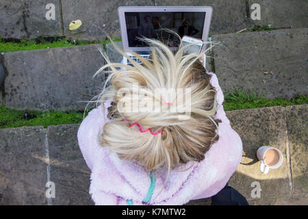 Une fille blonde se repose sur quelques mesures avec son ordinateur portable, téléphone mobile, une cigarette et une tasse de thé Banque D'Images